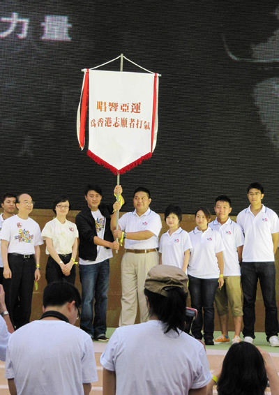 黎明及香港志愿者协会副主席林亨利先生从亚组委志愿者部宣传策划办公室副主任吕娜(右七)手中接过广州亚运会志愿者旗帜后,高高举起。右八为广播处长黄华麒先生。